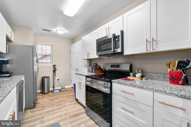 kitchen with visible vents, light stone countertops, light wood-type flooring, appliances with stainless steel finishes, and white cabinetry