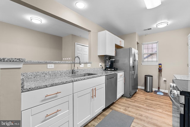 kitchen with visible vents, light wood-style flooring, a sink, white cabinetry, and stainless steel appliances