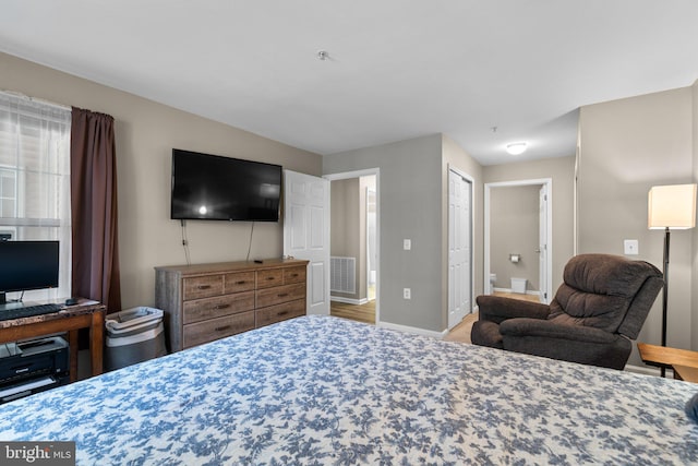 bedroom featuring baseboards, visible vents, and connected bathroom