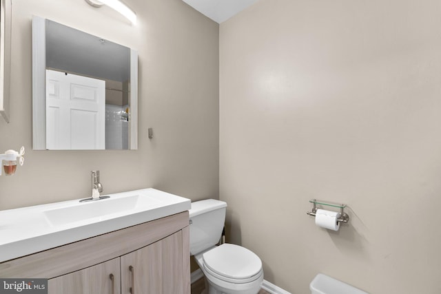 bathroom featuring vanity, toilet, and baseboards