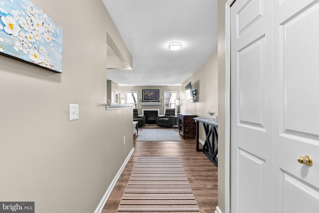 corridor with baseboards and wood finished floors