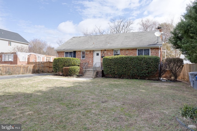 ranch-style home with brick siding, roof with shingles, a front yard, and fence