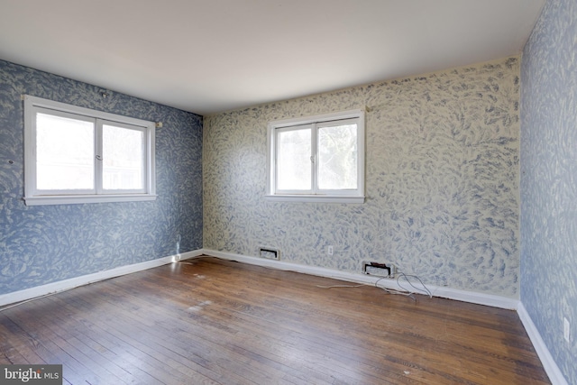 spare room featuring baseboards, hardwood / wood-style floors, and wallpapered walls