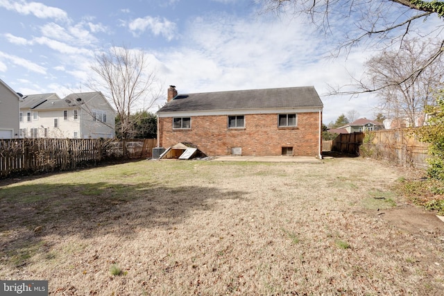 back of house with brick siding, a lawn, and a fenced backyard