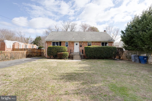 view of front of house featuring brick siding, fence, and a front lawn