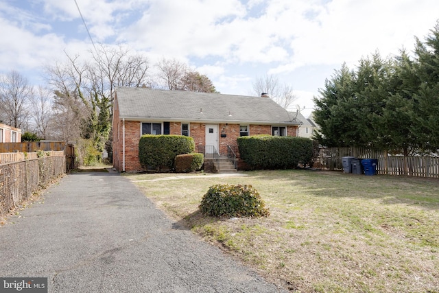 view of front of home featuring brick siding, a front yard, and fence