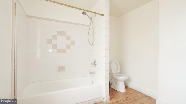 bathroom with baseboards, bathing tub / shower combination, toilet, and wood finished floors