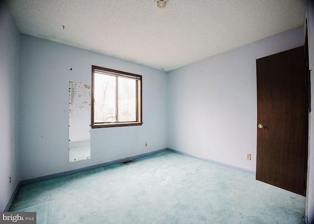 carpeted spare room with baseboards and a textured ceiling