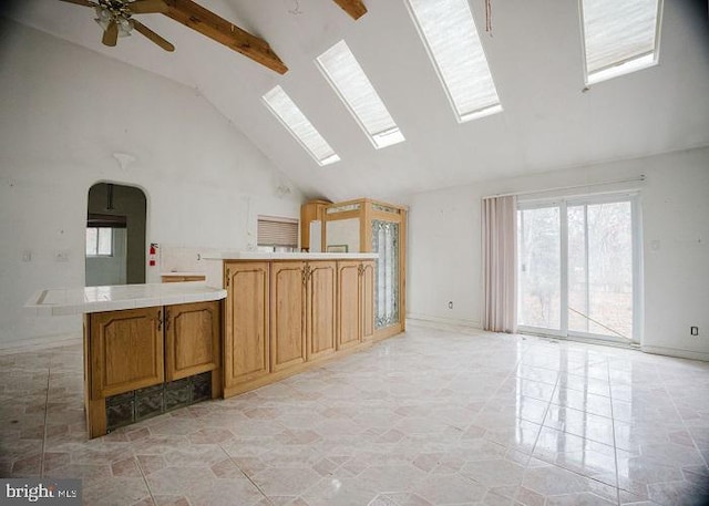 kitchen featuring arched walkways, high vaulted ceiling, a skylight, open floor plan, and beamed ceiling