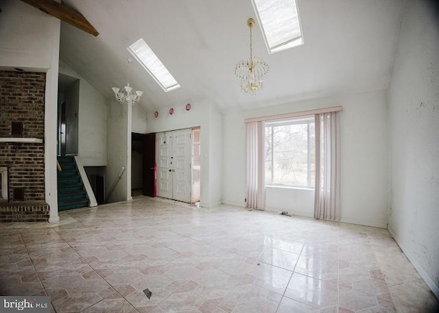 unfurnished living room featuring high vaulted ceiling, a skylight, a fireplace, stairway, and an inviting chandelier