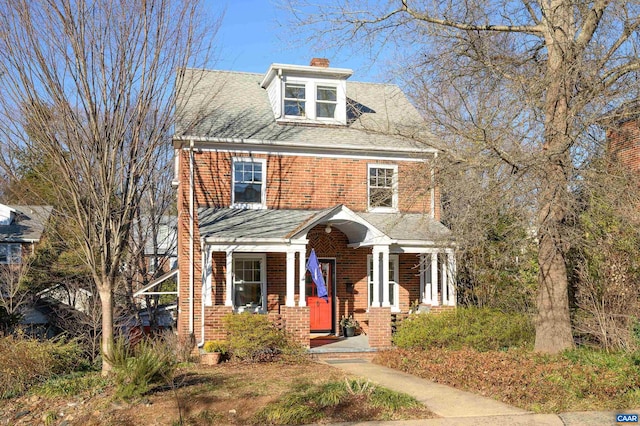 traditional style home featuring a shingled roof, a chimney, and brick siding