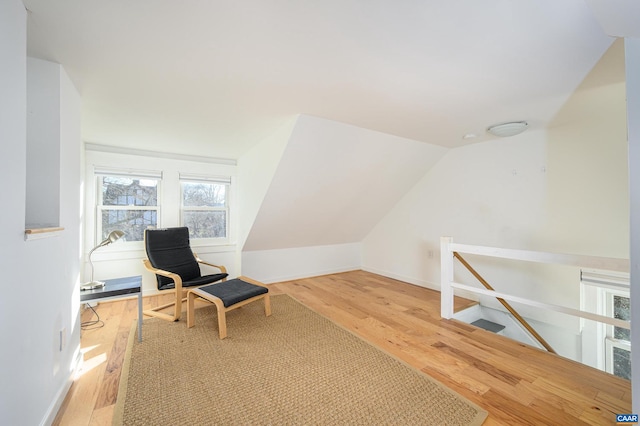 living area featuring baseboards, vaulted ceiling, an upstairs landing, and wood finished floors