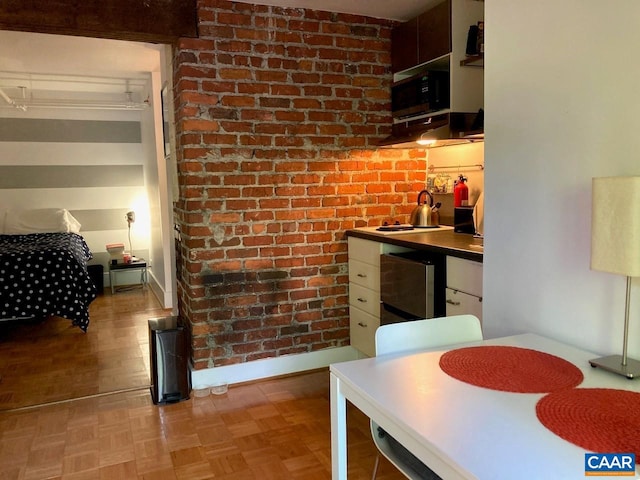 kitchen with dark countertops, brick wall, black microwave, and baseboards