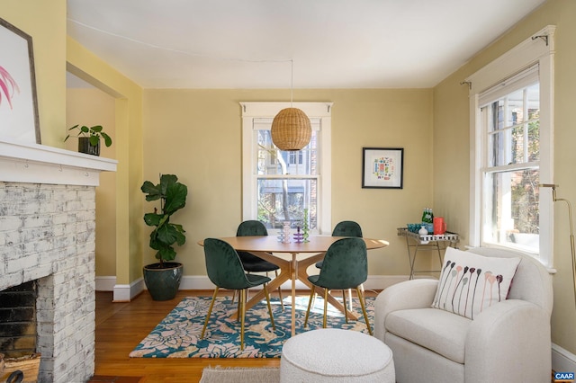 dining space featuring a fireplace, baseboards, and wood finished floors