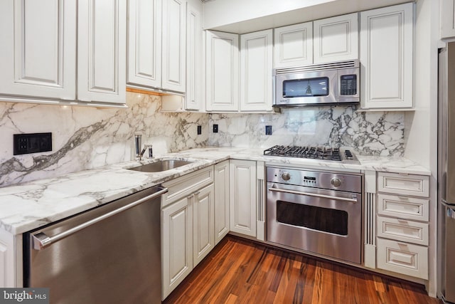 kitchen with light stone counters, dark wood-style flooring, appliances with stainless steel finishes, white cabinetry, and a sink