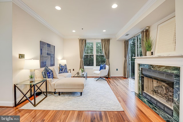 sitting room featuring recessed lighting, a premium fireplace, ornamental molding, baseboards, and hardwood / wood-style flooring