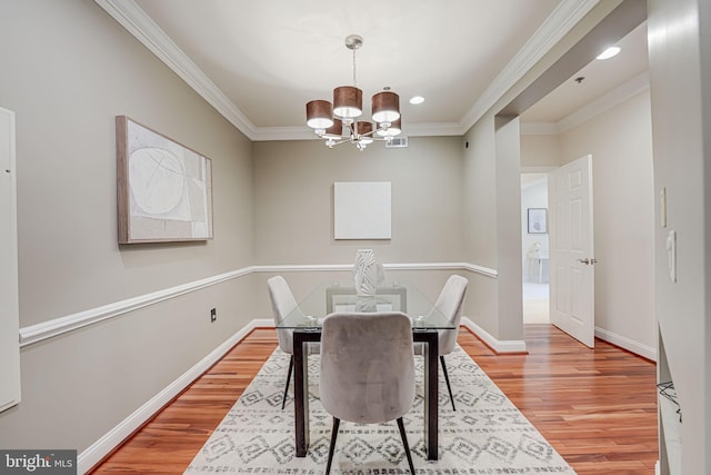 dining area featuring light wood finished floors, baseboards, a chandelier, and crown molding