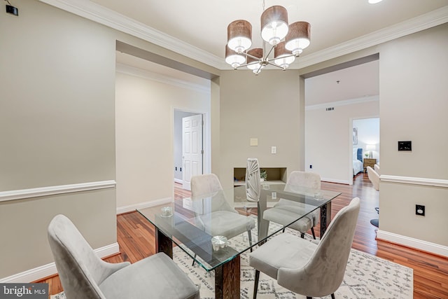 dining area featuring a chandelier, ornamental molding, wood finished floors, and baseboards