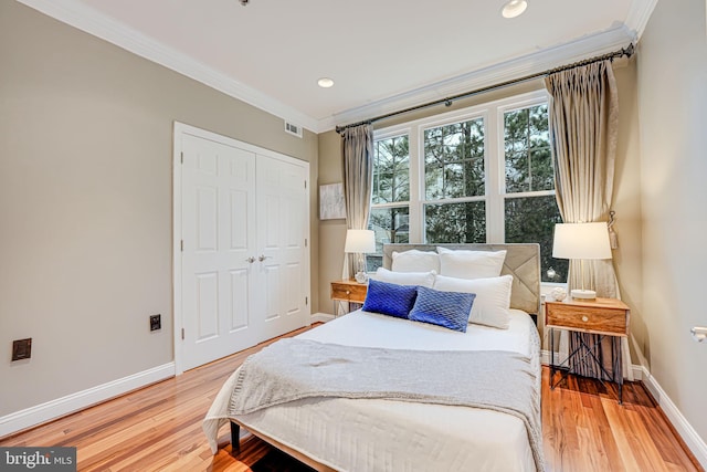 bedroom with visible vents, ornamental molding, light wood-style flooring, and baseboards