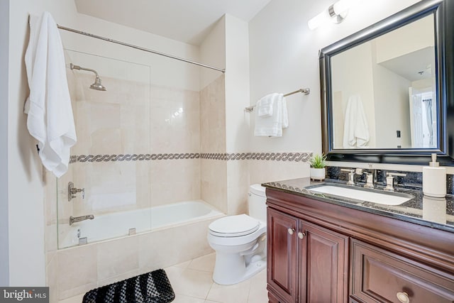 bathroom featuring toilet, tiled shower / bath combo, tile patterned flooring, vanity, and tile walls