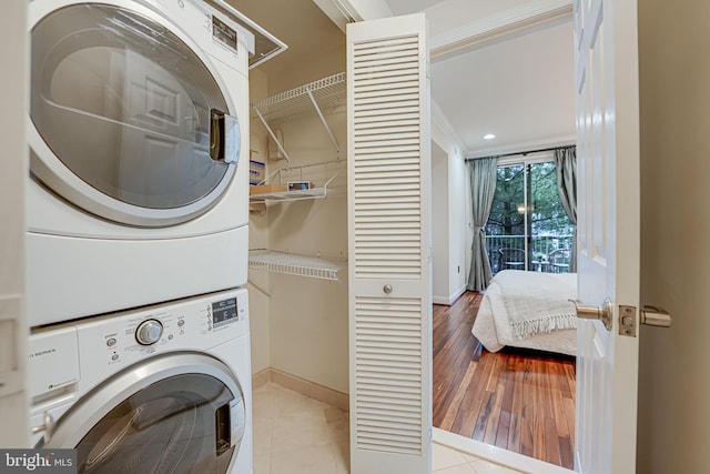 washroom with laundry area, stacked washing maching and dryer, tile patterned flooring, and baseboards