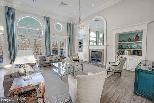 living area with visible vents, a tile fireplace, wood finished floors, french doors, and built in shelves