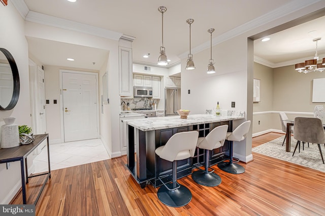 kitchen with tasteful backsplash, stainless steel microwave, crown molding, and a peninsula