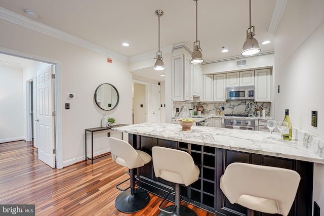 kitchen with light wood finished floors, appliances with stainless steel finishes, decorative backsplash, and ornamental molding