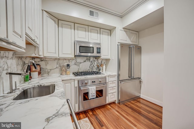 kitchen featuring visible vents, appliances with stainless steel finishes, a sink, crown molding, and backsplash