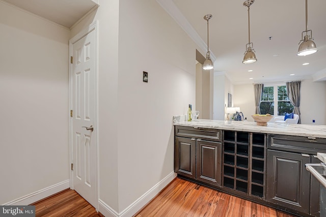 bar featuring baseboards, decorative light fixtures, light wood-style flooring, and crown molding