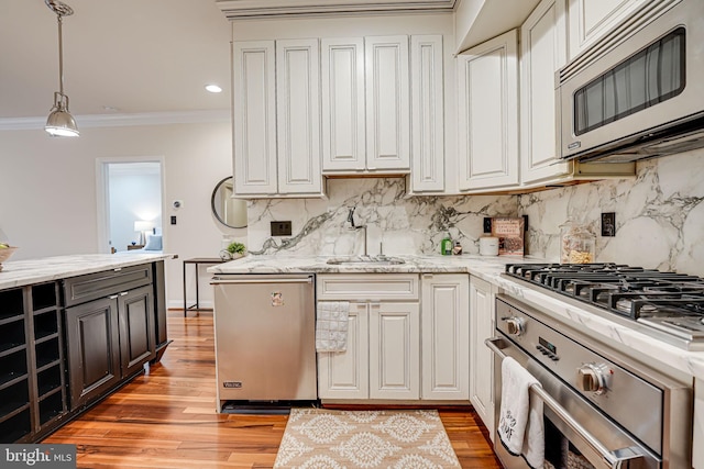 kitchen featuring stainless steel appliances, ornamental molding, a sink, and light wood-style flooring