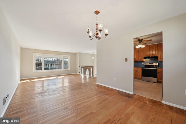 unfurnished living room featuring ceiling fan with notable chandelier, baseboards, visible vents, and light wood-type flooring