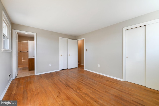 unfurnished bedroom featuring visible vents, baseboards, light wood-type flooring, and ensuite bathroom