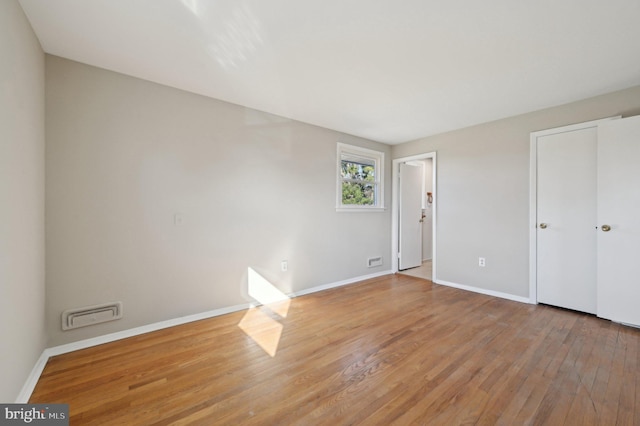 unfurnished bedroom with visible vents, wood finished floors, and baseboards