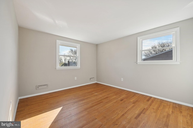 empty room with visible vents, wood finished floors, and baseboards