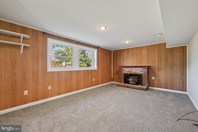 unfurnished living room with a brick fireplace, carpet, visible vents, and wood walls