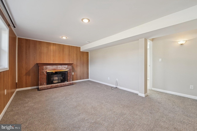 unfurnished living room featuring wooden walls, a fireplace, baseboards, and carpet