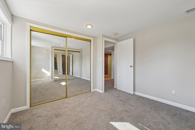 unfurnished bedroom with carpet flooring, baseboards, visible vents, and a closet