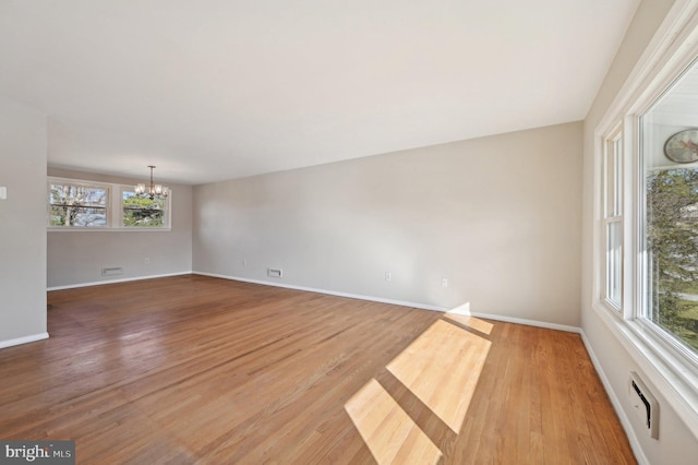 unfurnished room with a chandelier, baseboards, and wood finished floors