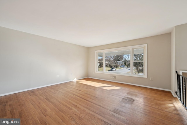 spare room featuring light wood-type flooring and baseboards