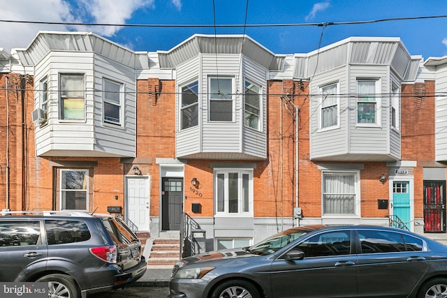 townhome / multi-family property with cooling unit and brick siding