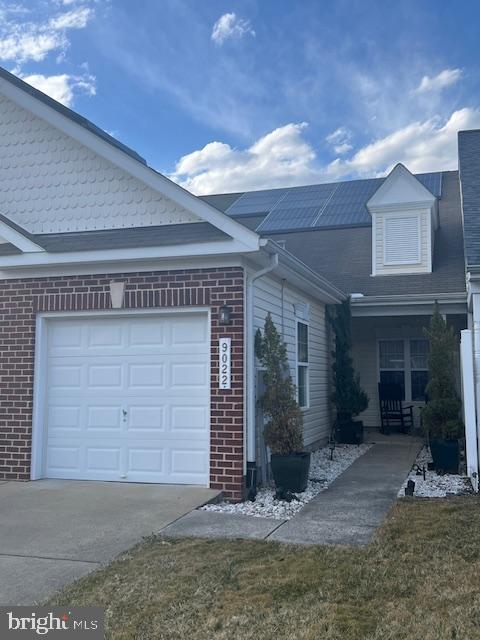 view of front of home with concrete driveway, brick siding, and an attached garage