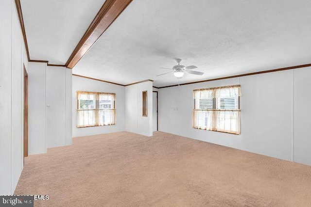 carpeted spare room featuring vaulted ceiling, crown molding, and ceiling fan