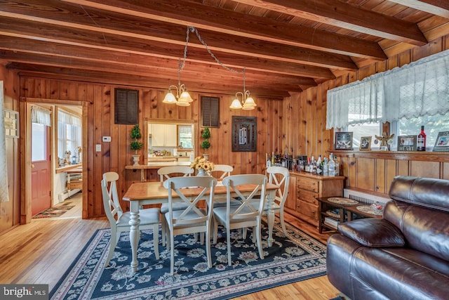 dining area with wooden ceiling, wooden walls, beamed ceiling, wood-type flooring, and an inviting chandelier