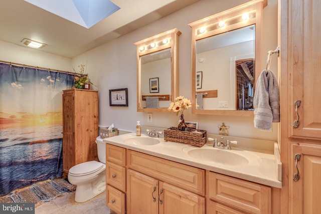 full bath with double vanity, a skylight, a sink, and toilet