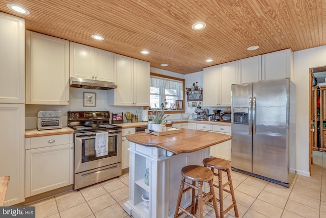 kitchen featuring butcher block counters, appliances with stainless steel finishes, under cabinet range hood, open shelves, and light tile patterned flooring