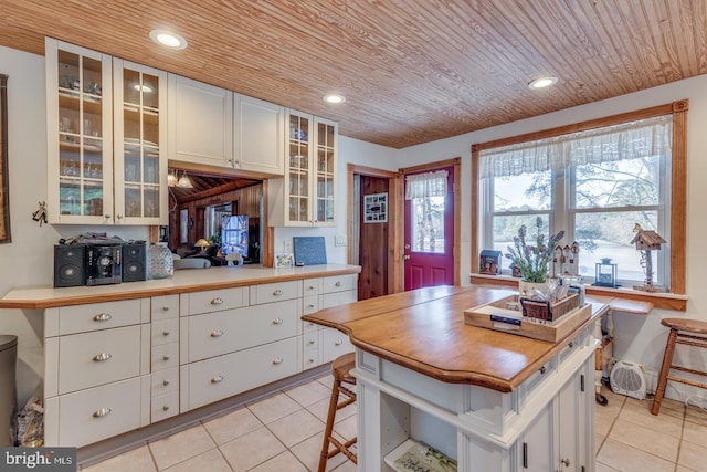 kitchen with glass insert cabinets, recessed lighting, wood ceiling, and light tile patterned floors