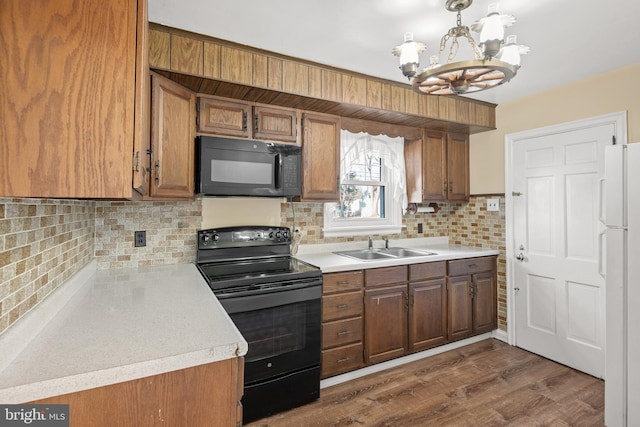 kitchen featuring brown cabinets, black appliances, light countertops, and a sink