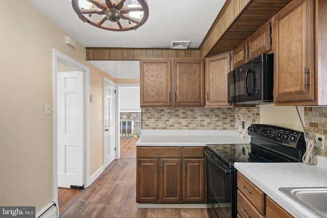 kitchen with a baseboard radiator, light countertops, visible vents, backsplash, and black appliances