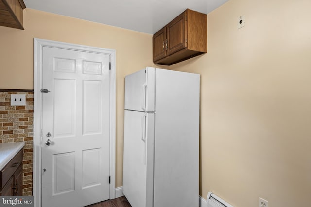 kitchen featuring light countertops, baseboard heating, freestanding refrigerator, and brown cabinets